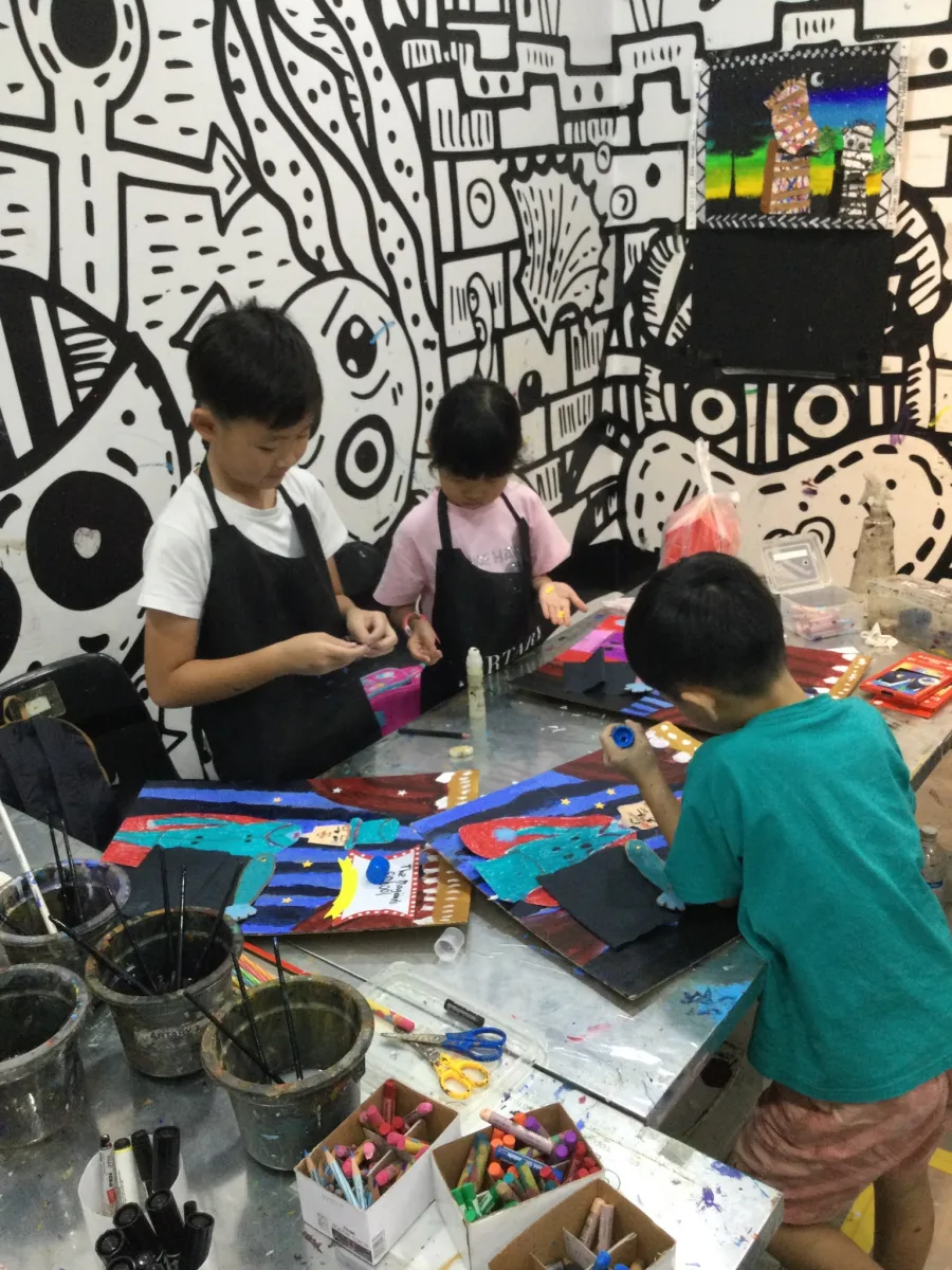 Children assembling colourful magician collages at a workshop table.